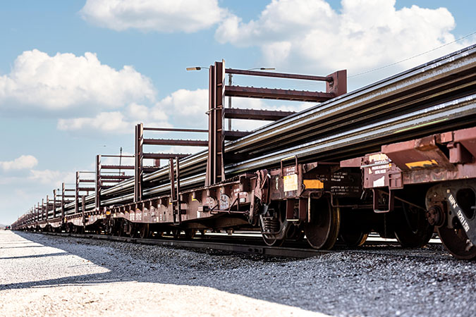 Finished continuous welded rail sticks being loaded onto specialized flat car racks for final transport