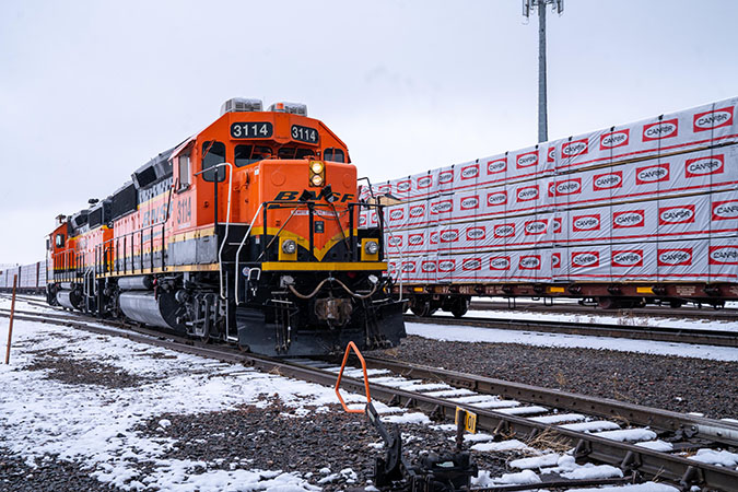 A remote-controlled locomotive parked next to centerbeam flatcars carries lumber at the Amarillo South Yard in Amarillo, Texas.