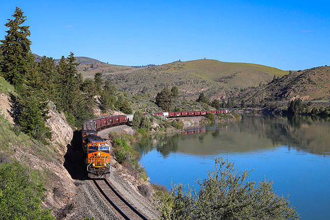 A Tier 4 locomotive leads a grain train eastbound along the Flathead River